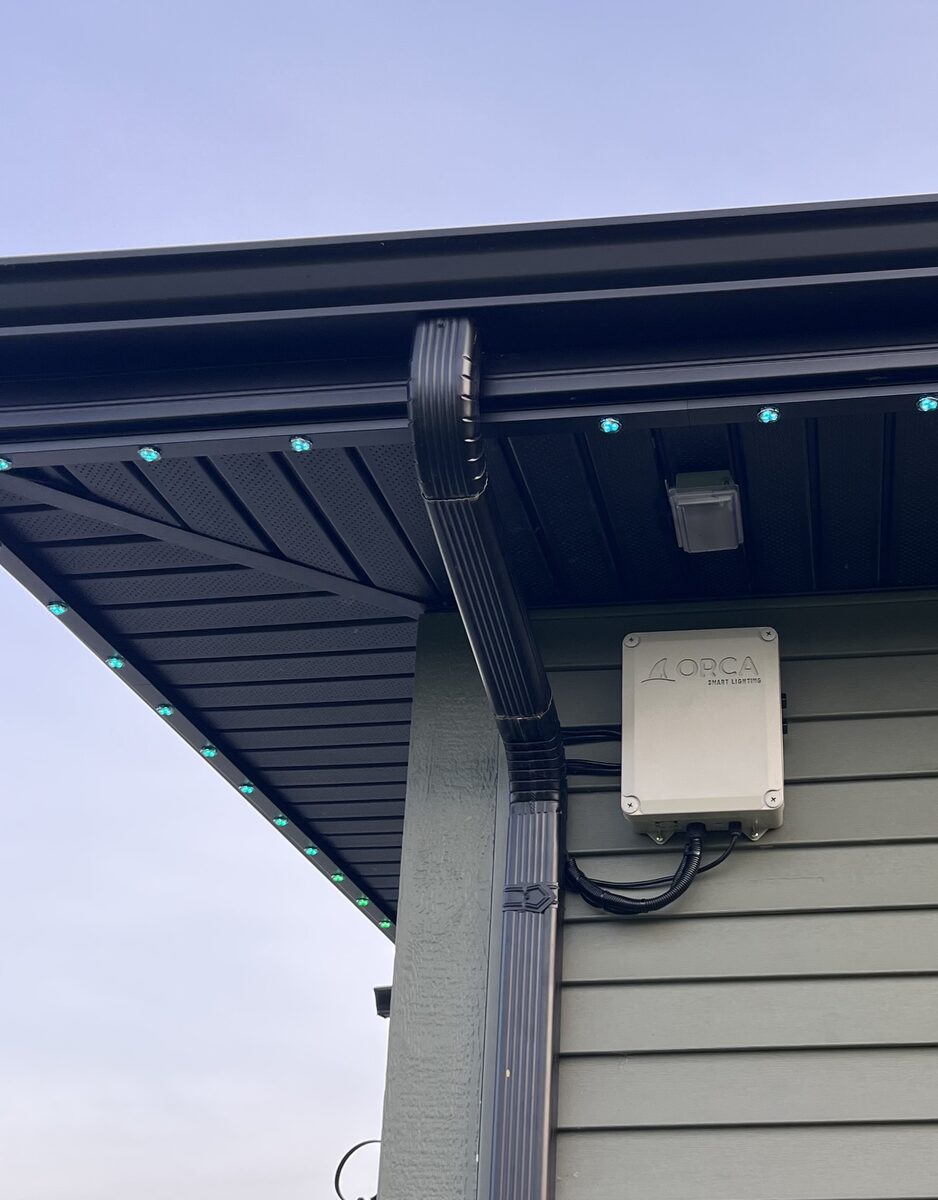 Orca controller box mounted under the eave beside the downspout